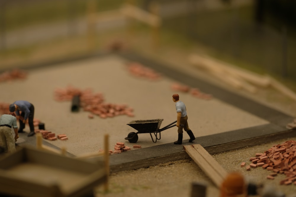 a miniature scene of a man pushing a wheelbarrow