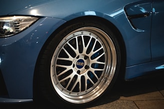 Close-up of a sleek sports car tire with electric blue accents on a city street at dusk.