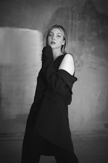 A close-up of a woman elegantly posing in a chic outfit against a backdrop of flashing cameras.