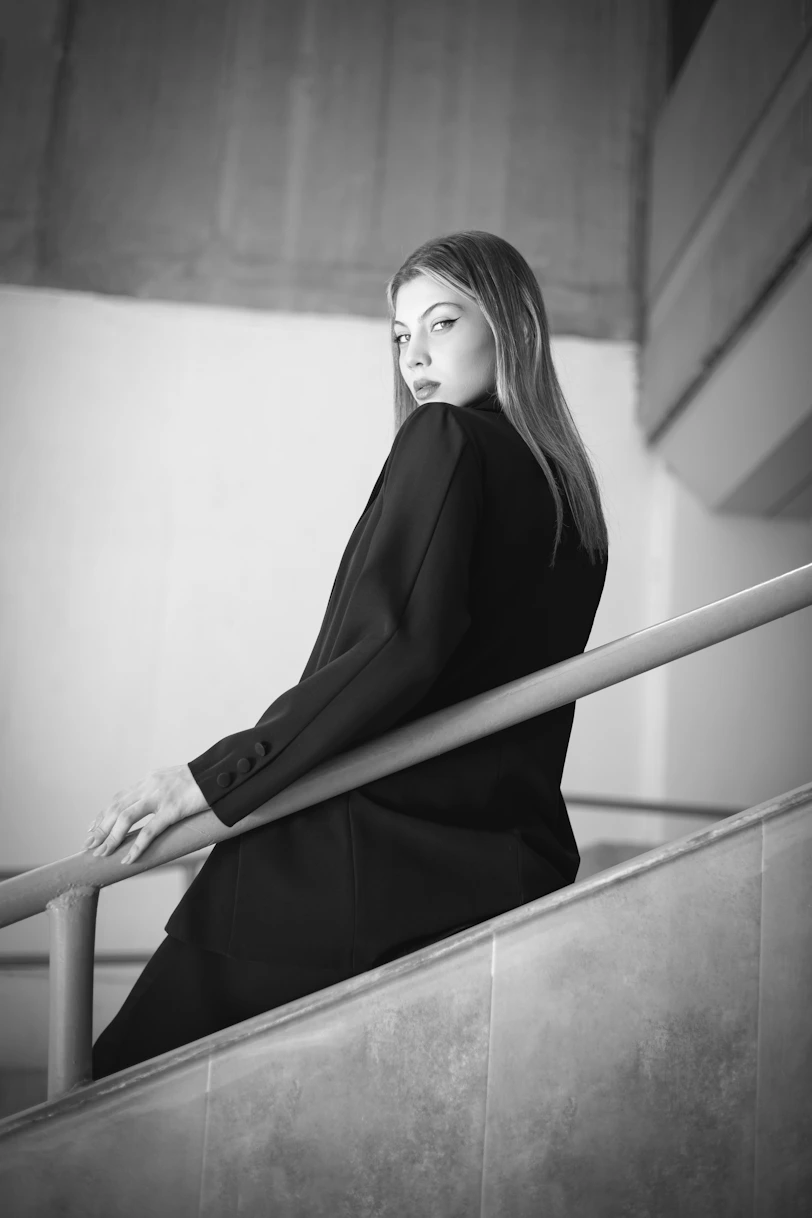 a black and white photo of a woman sitting on a railing