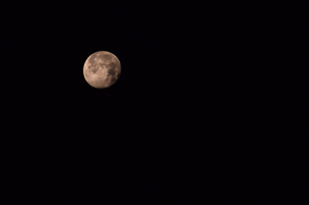 a full moon is seen in the dark sky