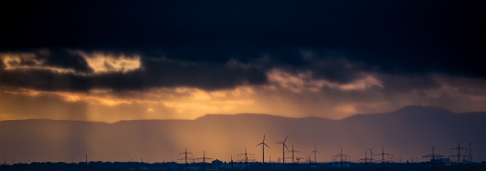 the sun shines through the clouds over wind mills