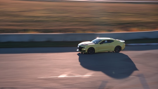 Close-up of a race car speeding on the track under bright sunlight.