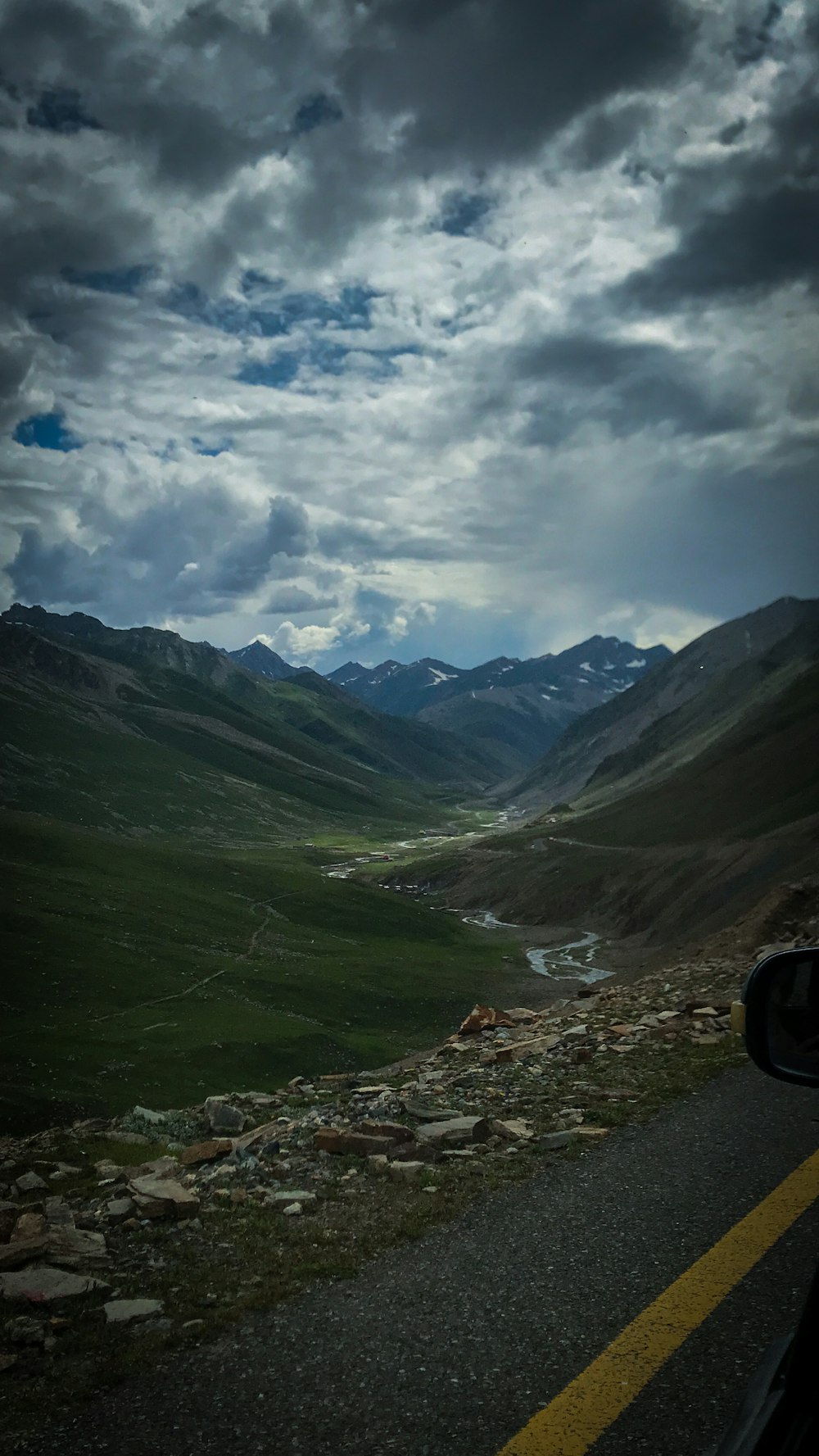 a scenic view of a valley and mountains under a cloudy sky