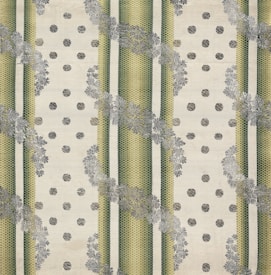 The image features a patterned textile design with alternating vertical green striped bands and beige dotted areas. The stripes have a textured, woven appearance, and floral motifs in grey overlay the stripes, creating a layered effect. The background has a soft, off-white hue, enhancing the contrast and detail of the patterns.