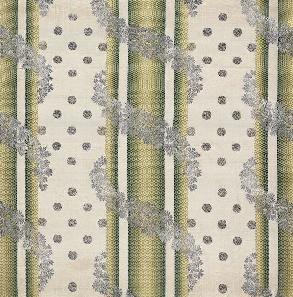 The image features a patterned textile design with alternating vertical green striped bands and beige dotted areas. The stripes have a textured, woven appearance, and floral motifs in grey overlay the stripes, creating a layered effect. The background has a soft, off-white hue, enhancing the contrast and detail of the patterns.