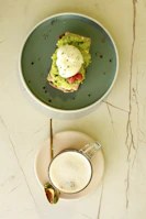Minimalist white plate with avocado toast garnished with cherry tomatoes and microgreens on a beige linen napkin.
