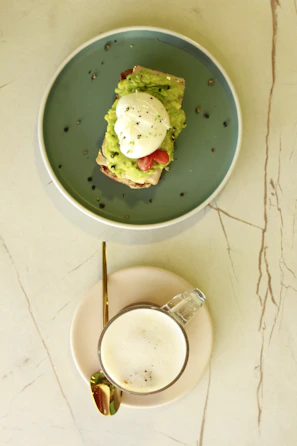Minimalist white plate with avocado toast garnished with cherry tomatoes and microgreens on a beige linen napkin.