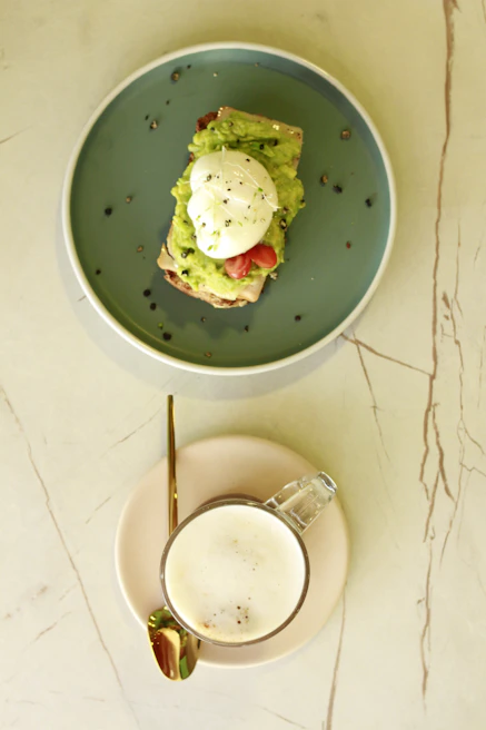 Elegant brunch plate featuring avocado toast topped with poached eggs and microgreens, styled on a white ceramic dish