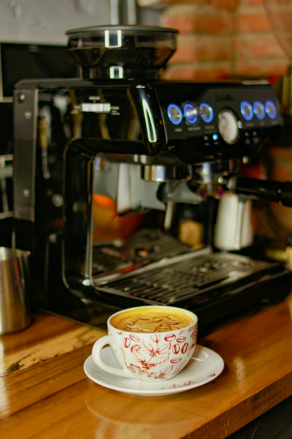una tazza di caffè seduta su un piattino accanto a una caffettiera