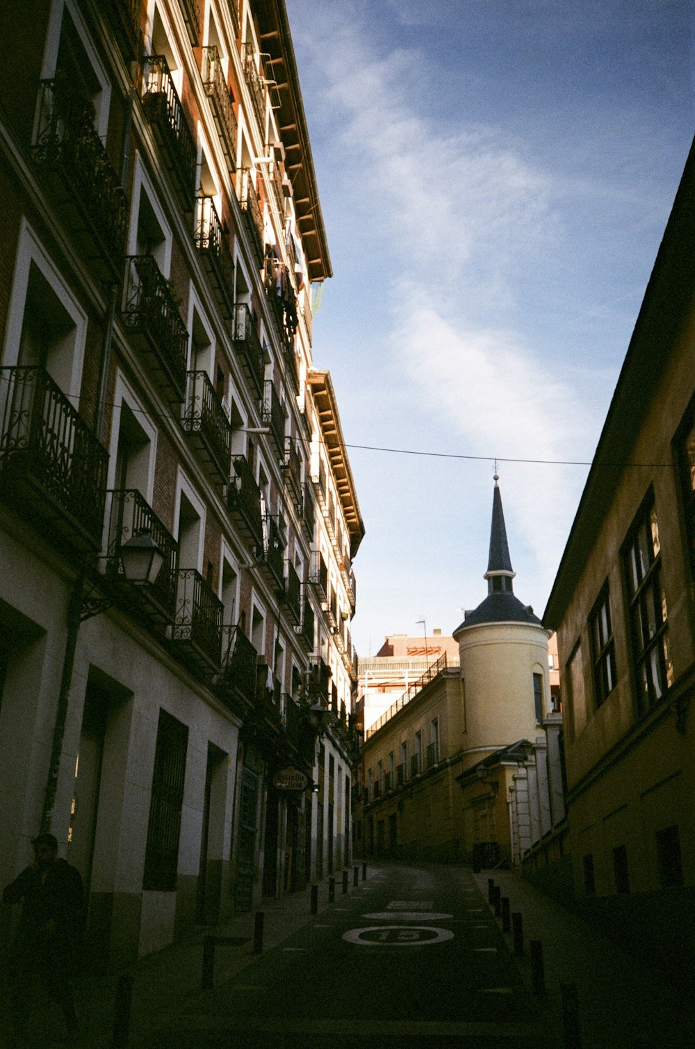 a narrow street with a clock tower in the background