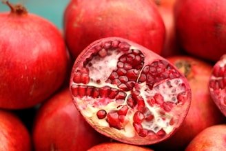 A close-up of fresh onions and pomegranates on a wooden table.