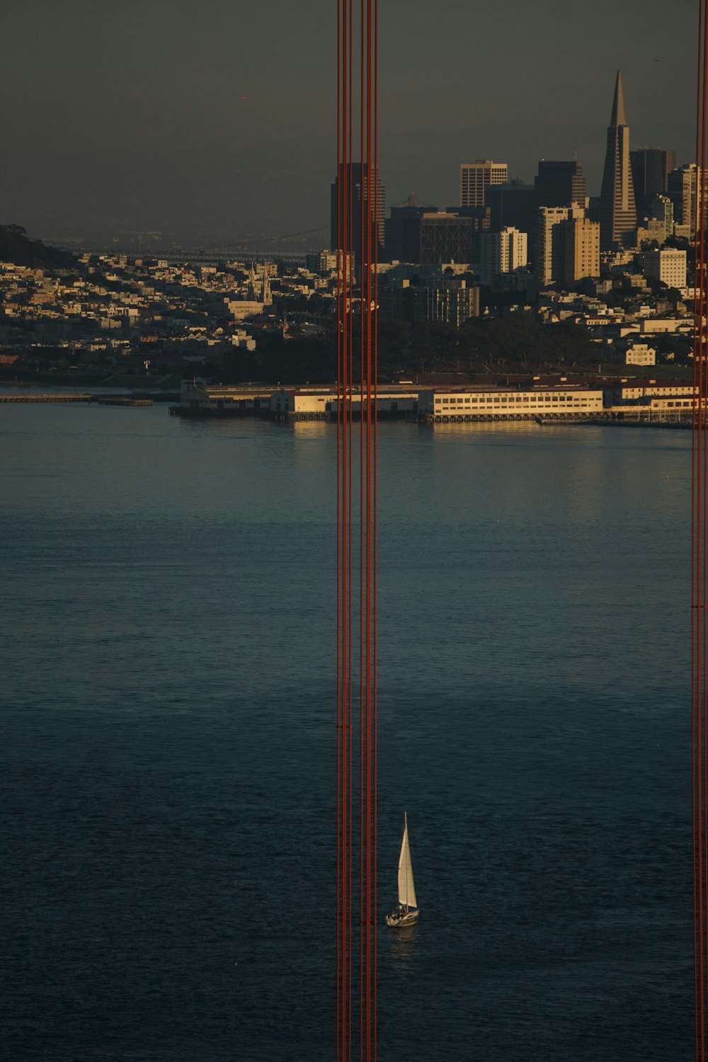 a sailboat in the water with a city in the background