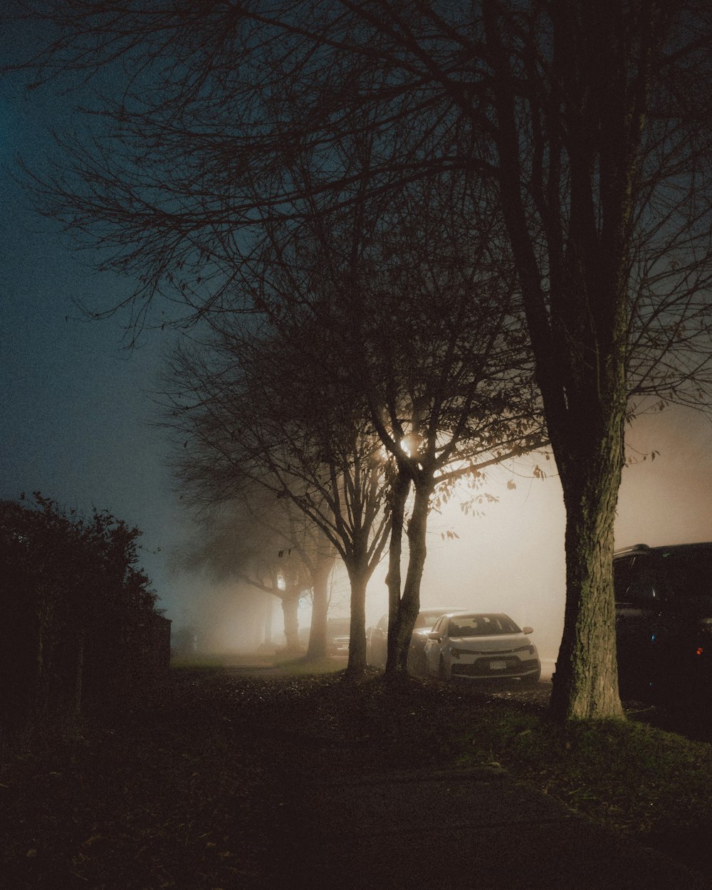 a foggy night with cars parked on the side of the road