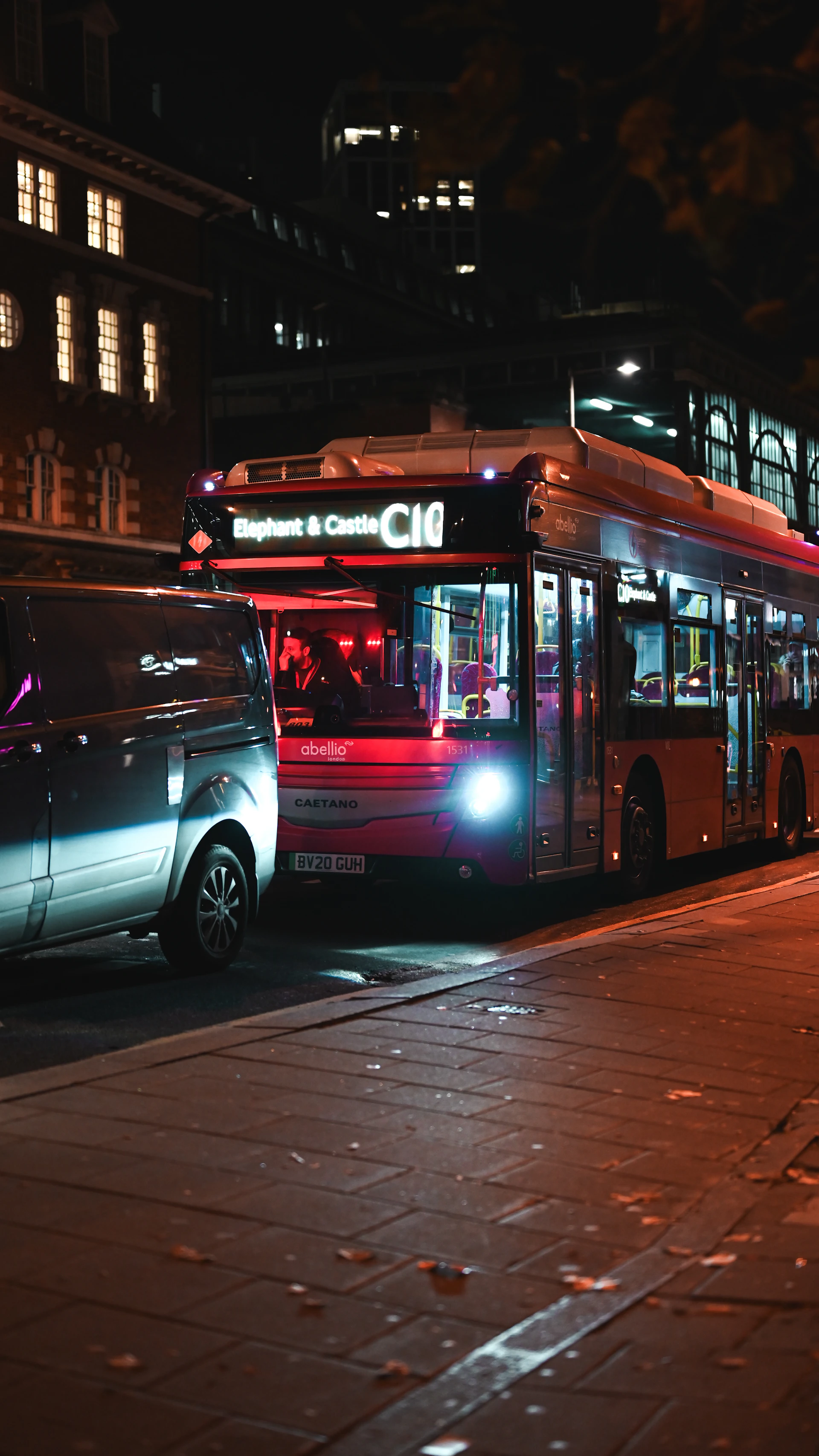 a bus and a car on a city street at night