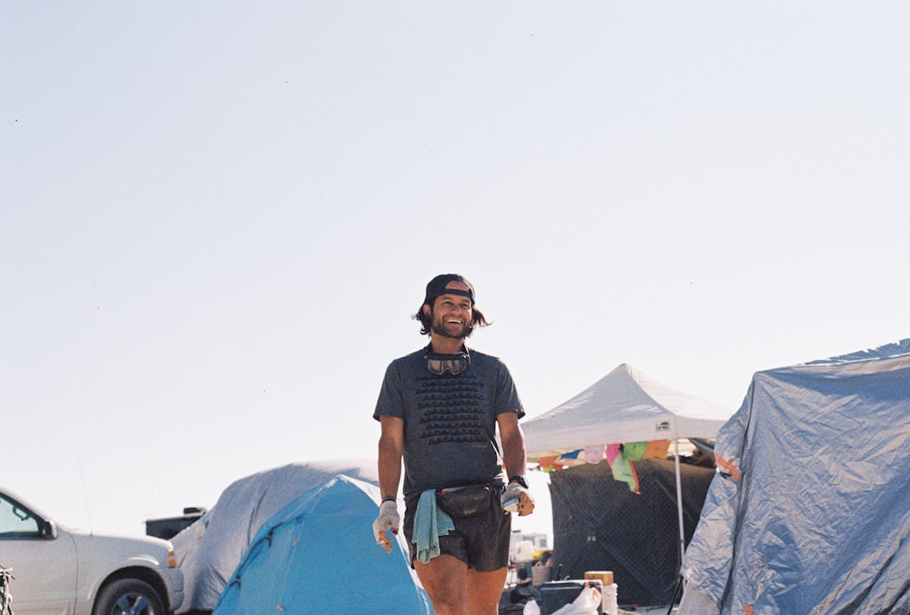 a man standing in front of a tent with a surfboard