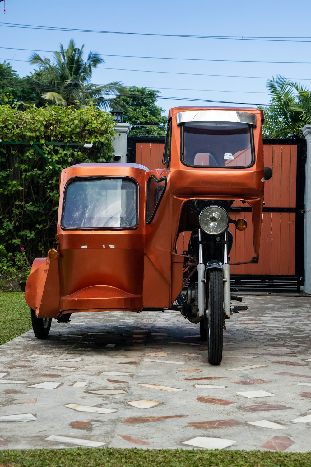 an orange car parked in front of a gate