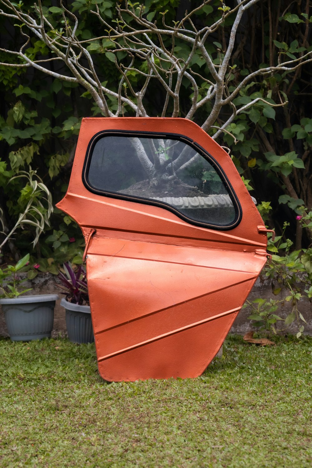 an orange sculpture sitting on top of a lush green field