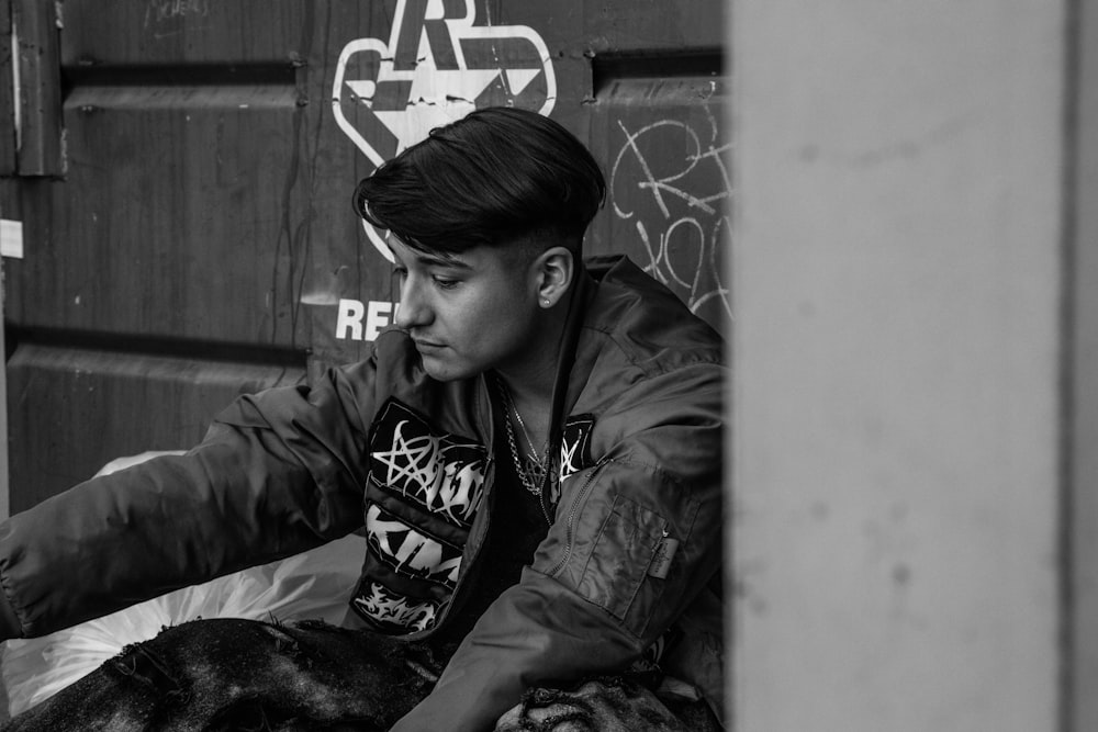 a young man sitting on the ground next to a dog