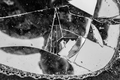 A cracked mirror reflecting a fragmented cityscape.