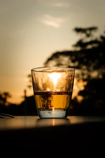 A glass of golden Seabuckthorn Juice catching sunlight on a rustic wooden table.