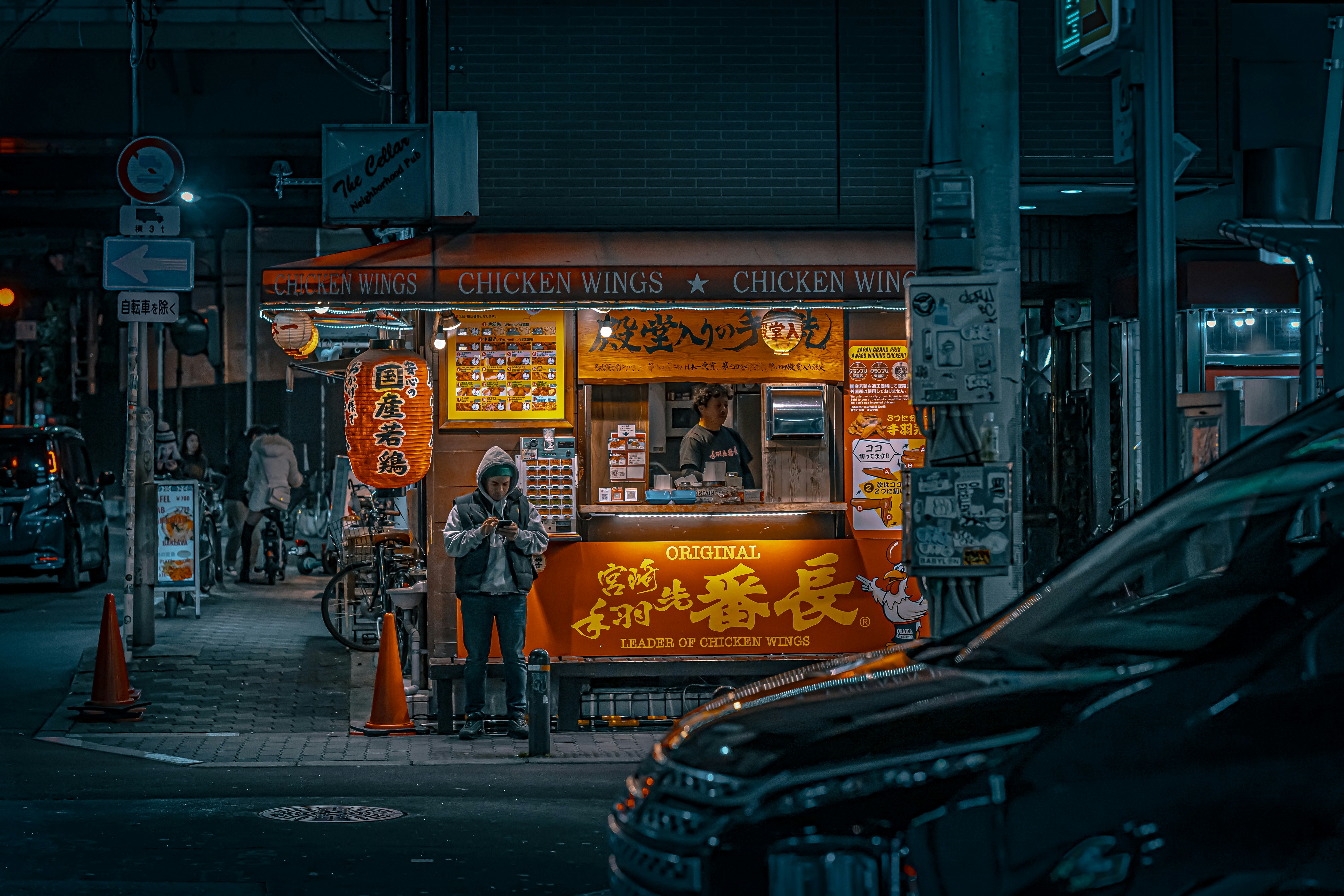 a woman standing in front of a food stand at night