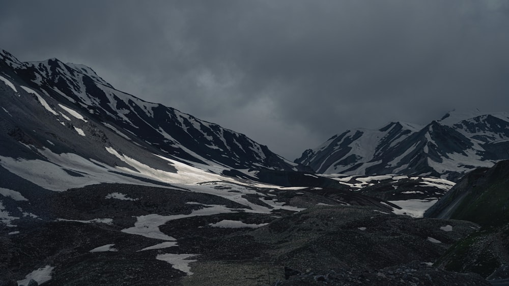 a snow covered mountain range under a cloudy sky