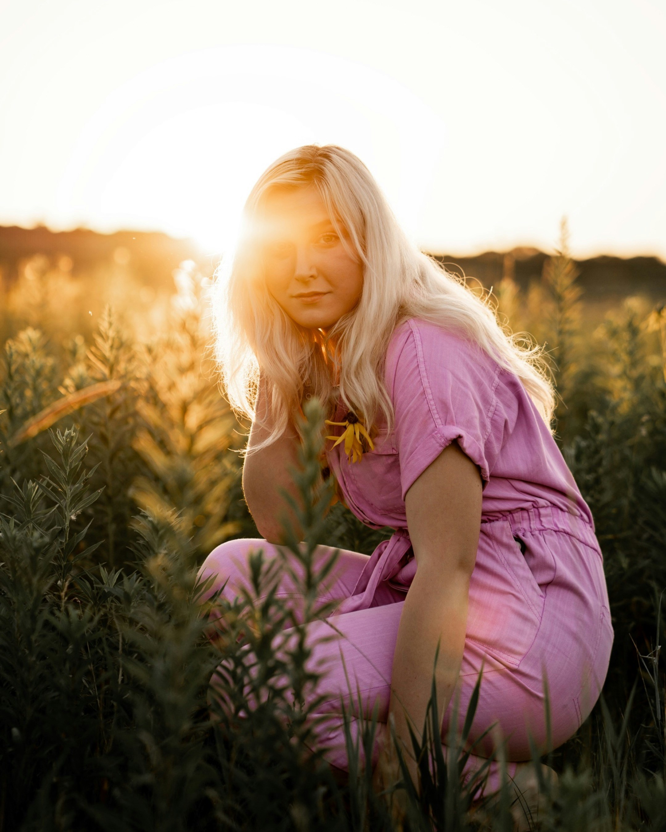 a woman kneeling down in a field of tall grass