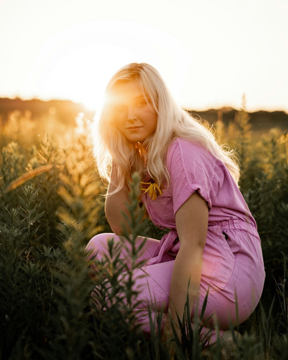 une femme agenouillée dans un champ d’herbes hautes