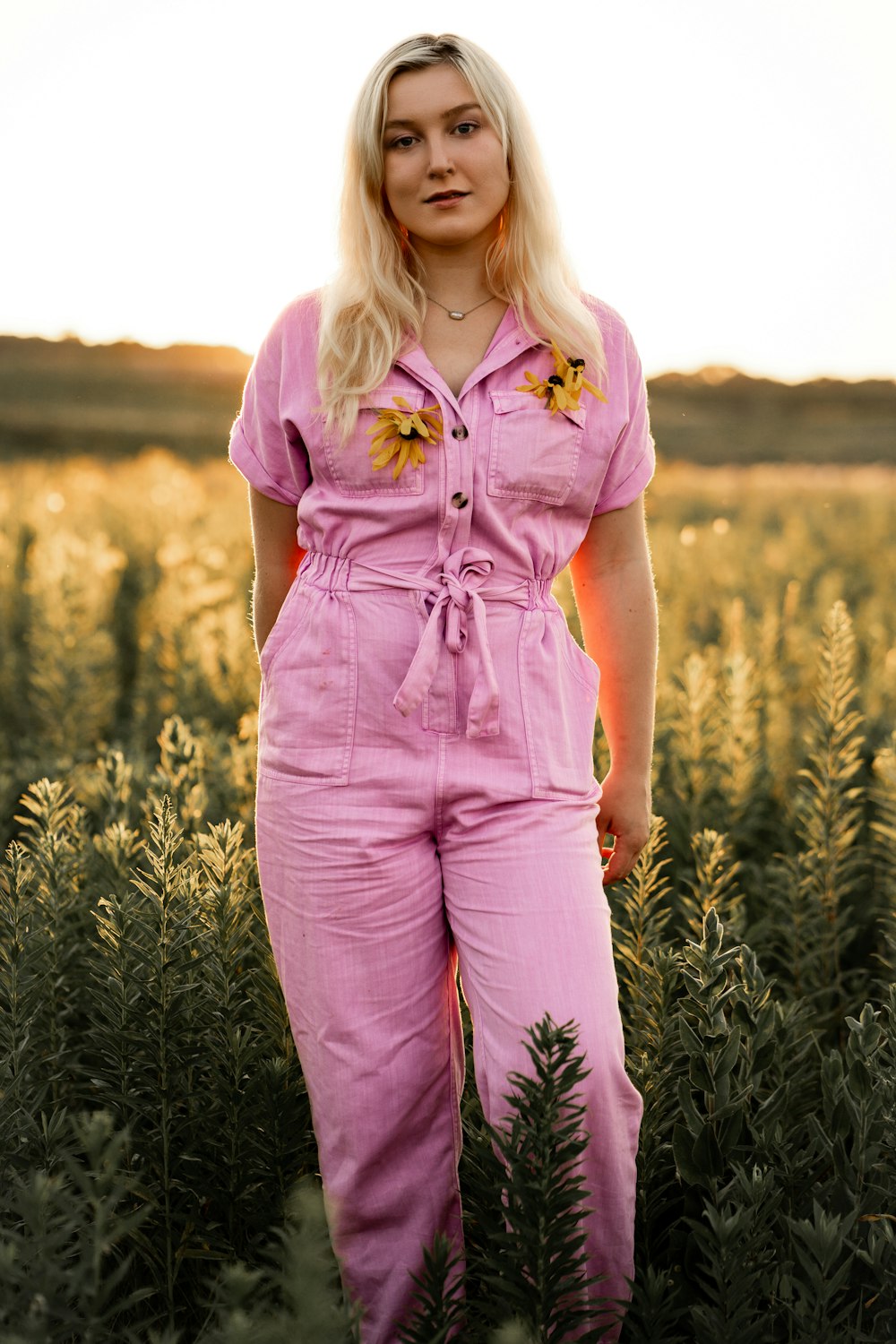 a woman in a pink jumpsuit standing in a field