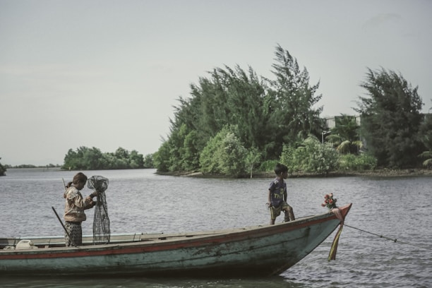 A happy couple holding fishing rods on a boat surrounded by lush green reeds and blue water.
