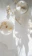 A softly glowing candle in a minimalist recyclable vessel set on a wooden table with dried wildflowers.