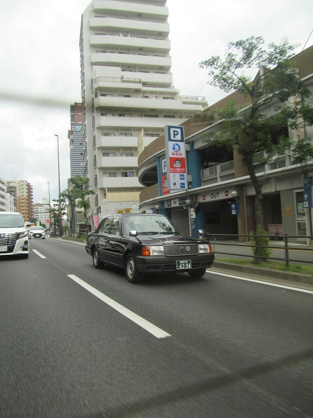 a black car driving down a street next to tall buildings