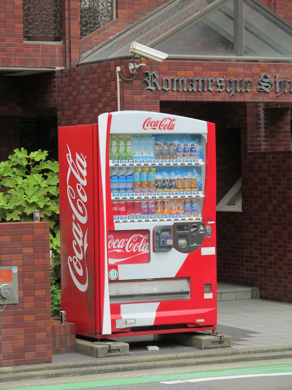 a red and white vending machine sitting outside of a building