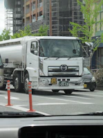 A delivery truck parked outside a commercial building with water tanks being filled