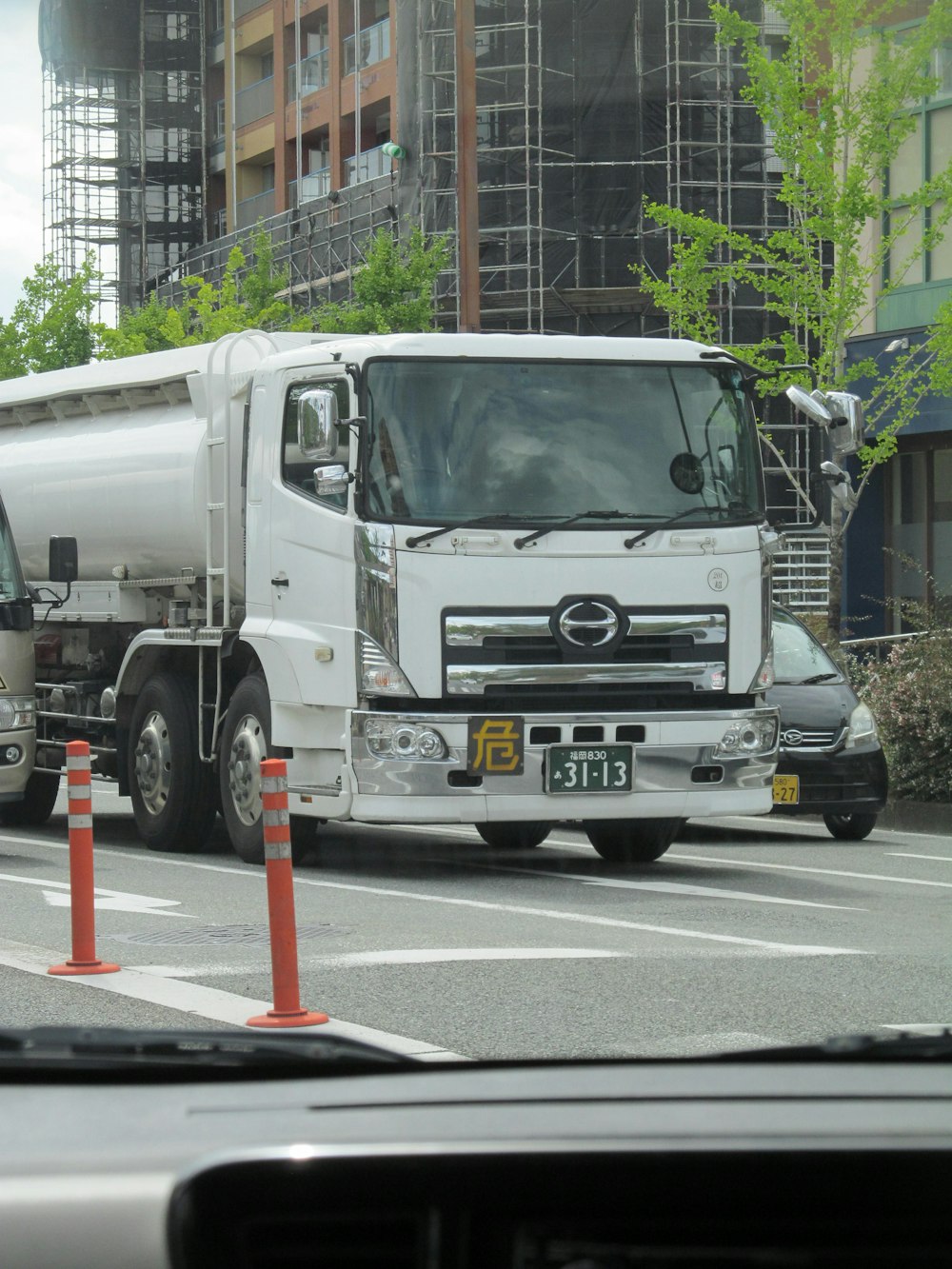 a white truck driving down a street next to tall buildings