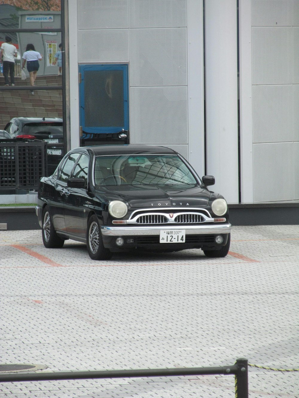 a small black car parked in front of a building