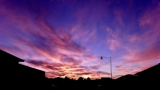 A vibrant purple sunset over a quiet city skyline, symbolizing hope and reflection.