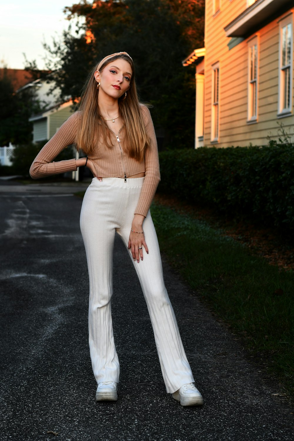 a woman in white pants and a brown sweater