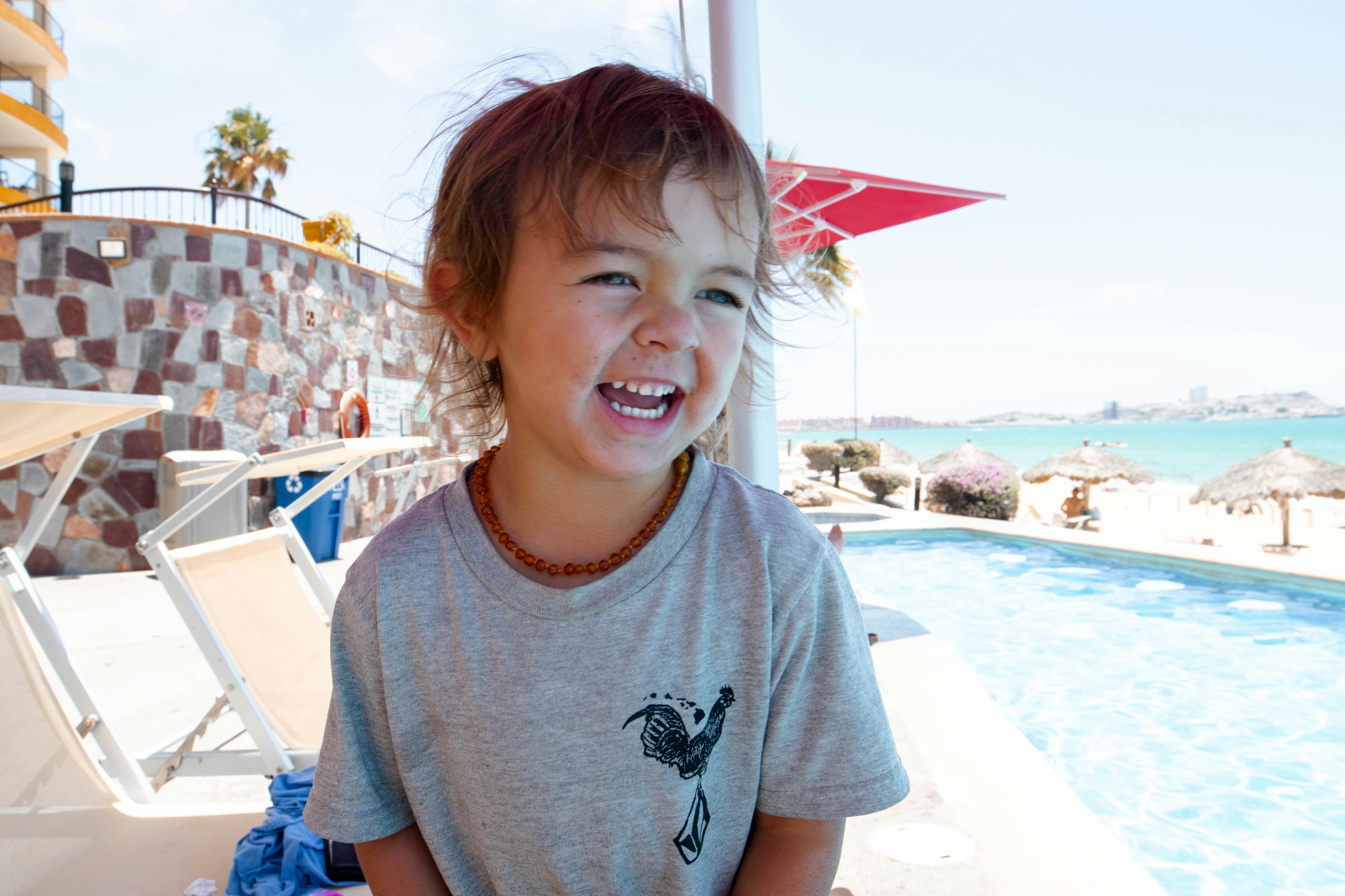 a little girl standing next to a swimming pool