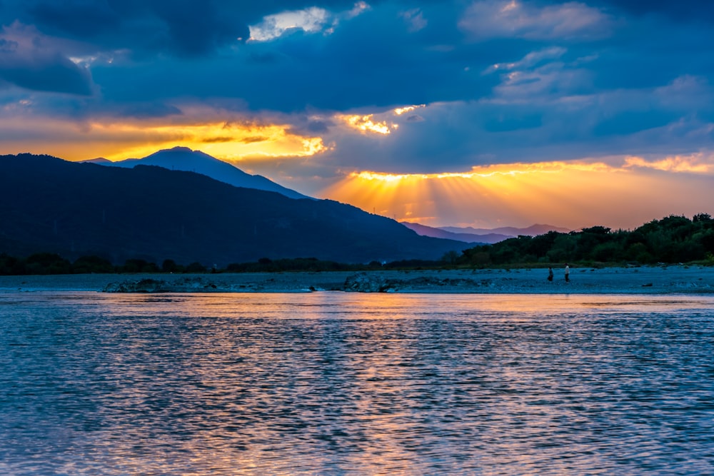 the sun is shining through the clouds over a body of water