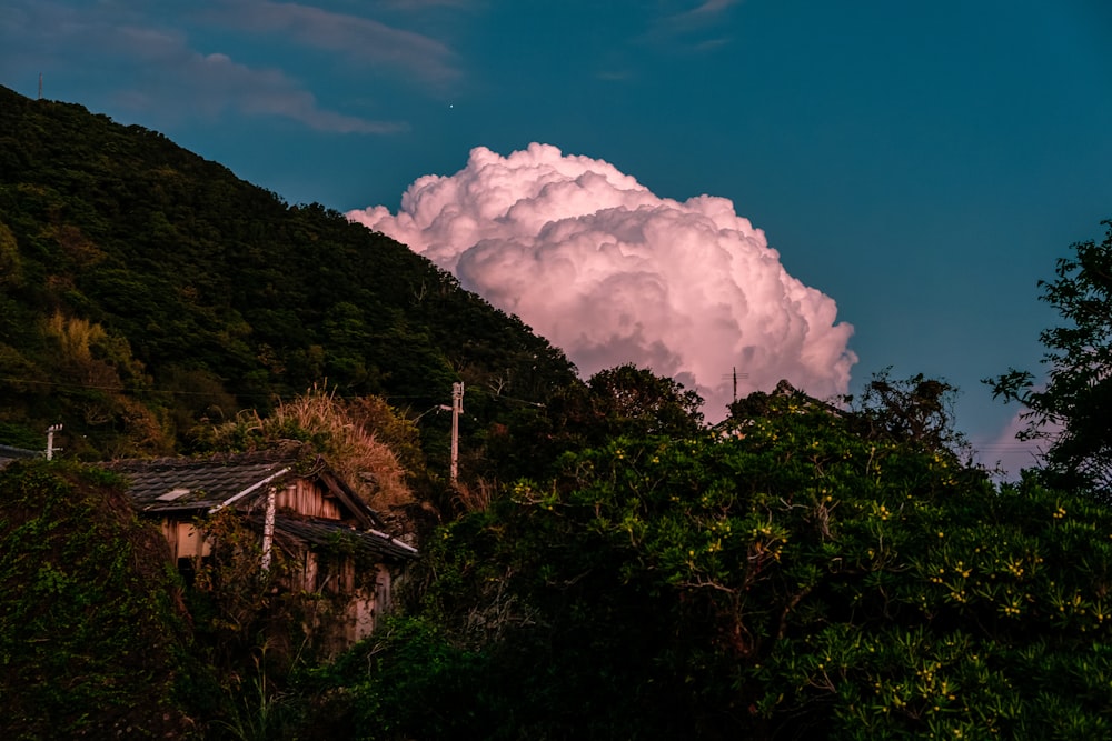 a large cloud looms over a house in the mountains