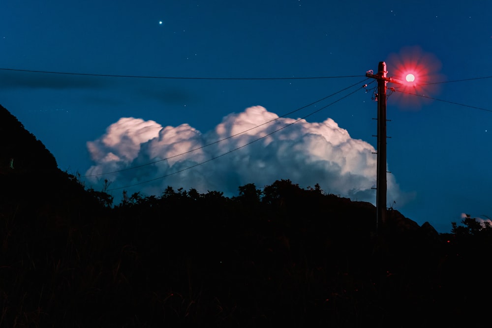 a red street light sitting on the side of a hill