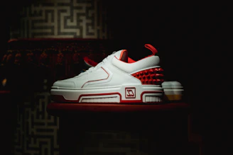 A stylish pair of men's high-end sneakers showcased on a sleek, minimalist pedestal.