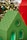A brightly colored decorative model of a house with a green roof and black geometric patterns is in the foreground. The house features cut-out windows and circular designs. In the background, warm, blurred lights resembling bokeh effects suggest a festive or holiday setting.