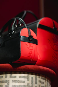 A collection of bold red and black statement handbags with gold hardware displayed on a velvet cloth.