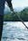 A rowing coach helping an athlete adjust their oar on a sunny riverbank.