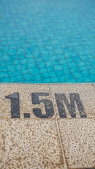 A tiled pool edge is visible with a depth marking of 1.5 meters. The pool water has a clear blue color with a textured, tiled surface beneath.