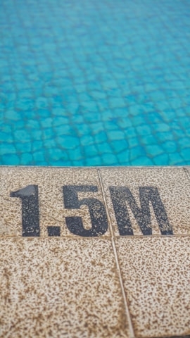 A tiled pool edge is visible with a depth marking of 1.5 meters. The pool water has a clear blue color with a textured, tiled surface beneath.