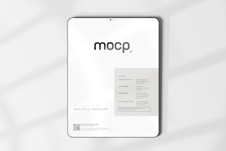 A digital mockup featuring a tablet with a minimalistic design. The screen displays a sleek interface with the word 'mocp' prominently at the top. Below it, there's information about features such as very realistic output and fully editable resolution. The background is clean and white, accented by soft shadows.
